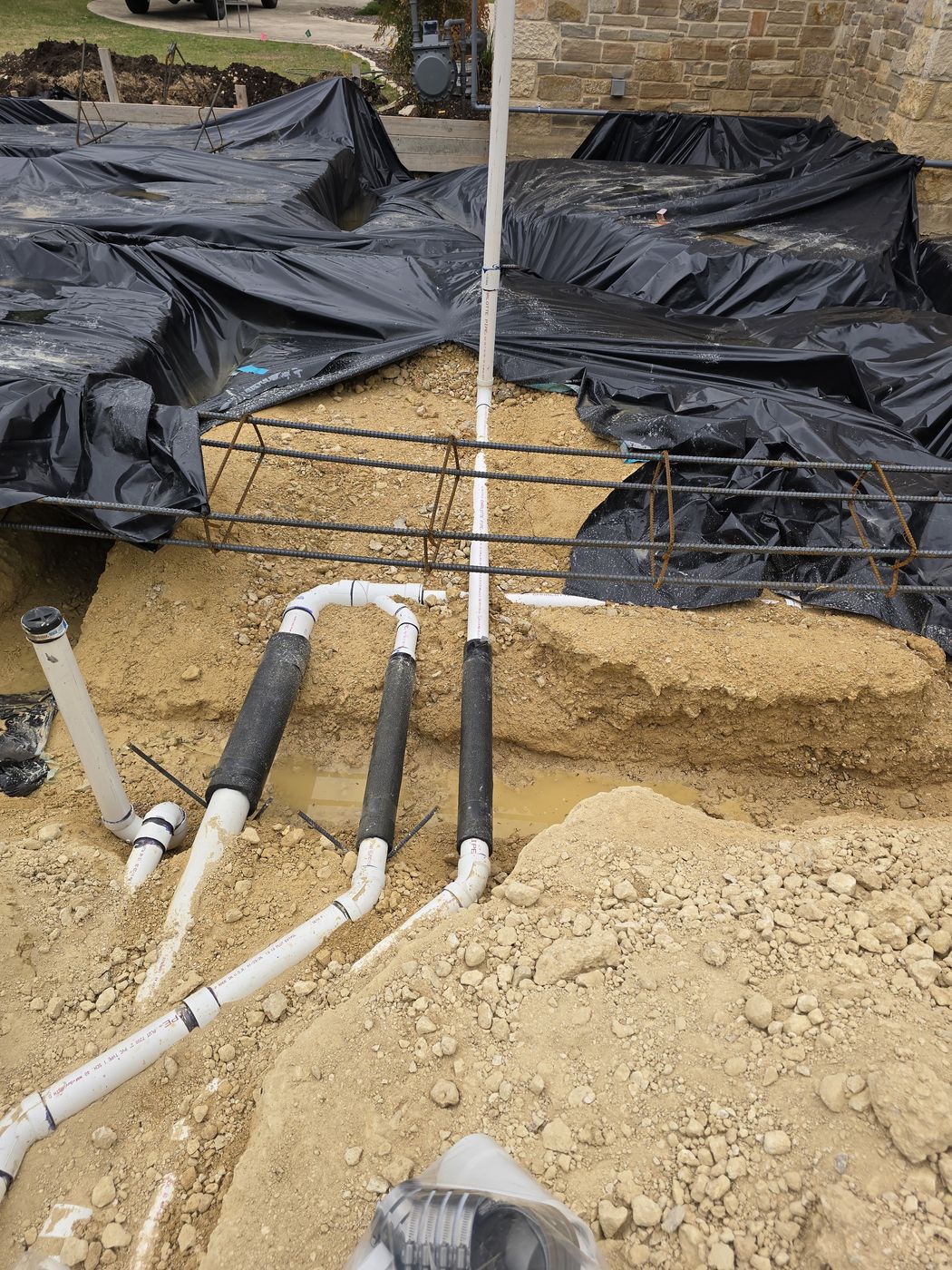Under-slab plumbing rough-in over vapor barrier and rebar before the pour