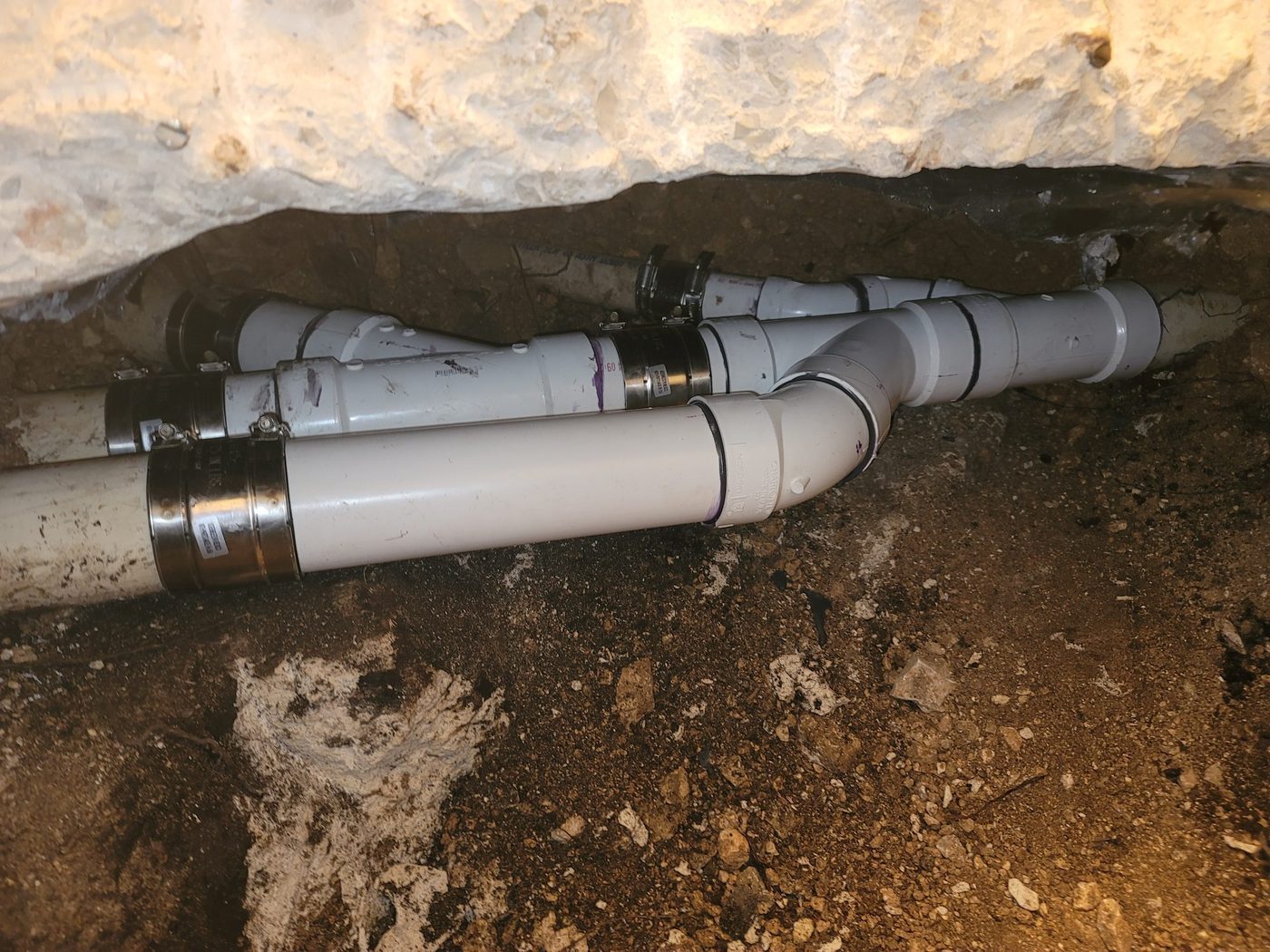 A drain assembly built on a rock shelf under a slab, joined with shielded couplings