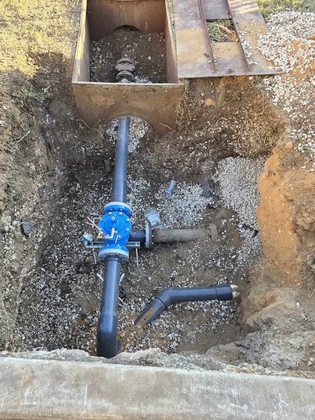 A water main and gate valve set in a trench with a trench box in place
